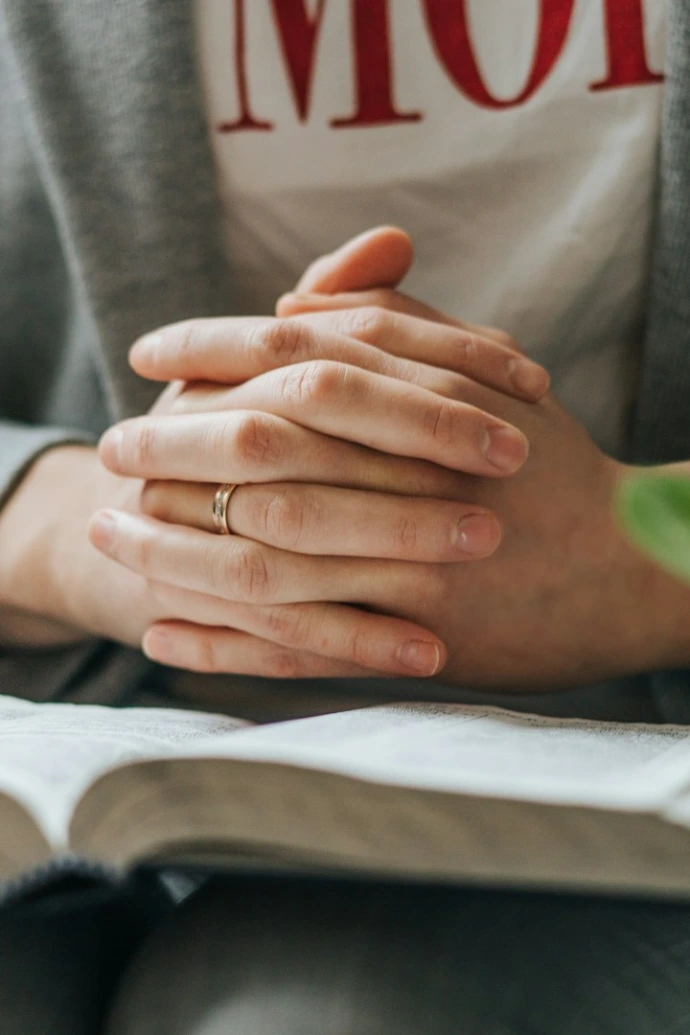 a person sitting down with their hands folded over a book